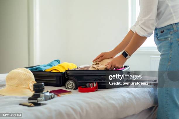 woman preparing suitcase for holidays - bezittingen stockfoto's en -beelden