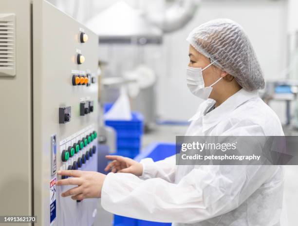 una mujer con traje limpio completamente blanco operando un panel de control del interruptor - mono blanco traje protector fotografías e imágenes de stock