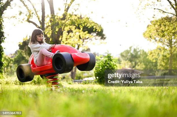 happy childhood concept. little girl in a sunny park swinging on red car. - i pace concept car stock pictures, royalty-free photos & images