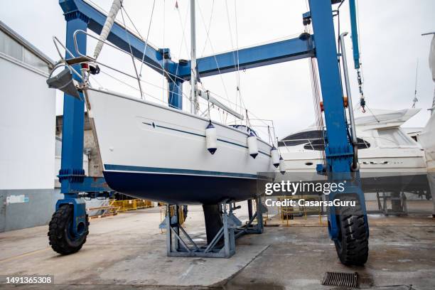 schiffshebewerk, das segelboote während des winters an land zur lagerung bringt - trocknen stock-fotos und bilder