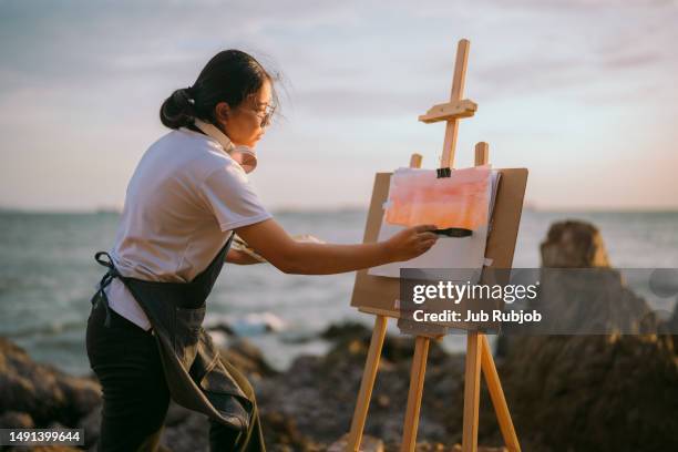 woman painting by the sea - asia ray stock-fotos und bilder