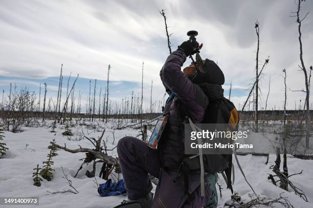 SnowEx researcher master's student Sage Ebel takes a hemispherical photo in a section of old burned boreal forest during the melt season on May 3,...