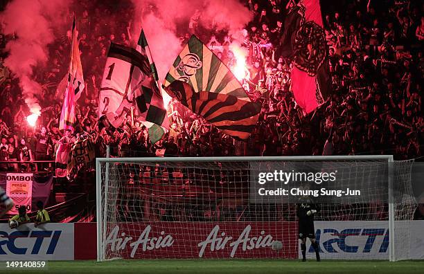 Fans set of flares during the preseason friendly match between Persebaya and Queens Park Rangers at Gelora Bung Tomo Stadium on July 23, 2012 in...