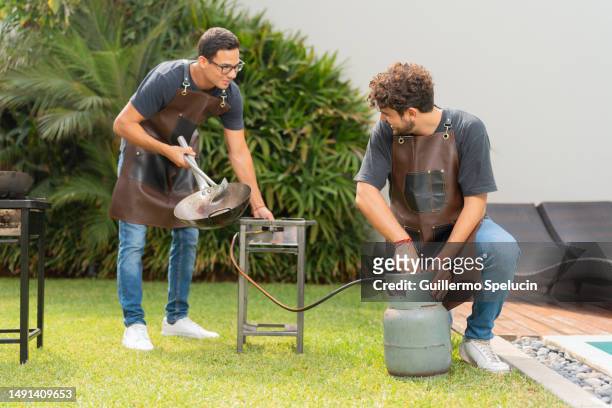 friends on a garden preparing a barbecue working with gas - bbq apron stock pictures, royalty-free photos & images