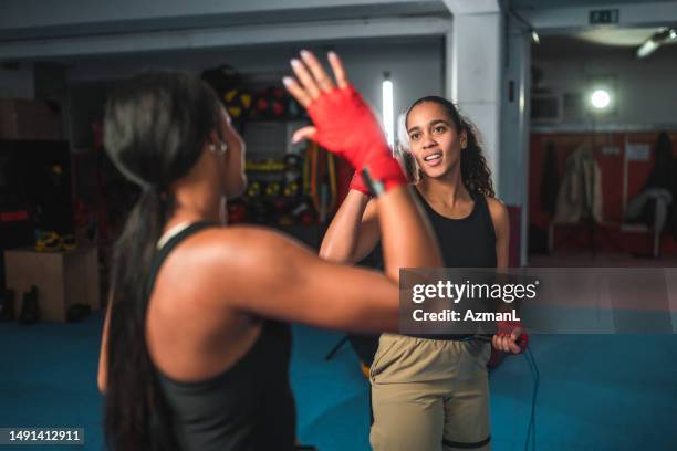 zwei gemischtrassige frauen machen high five, während sie zusammen boxen - mixed boxing stock-fotos und bilder