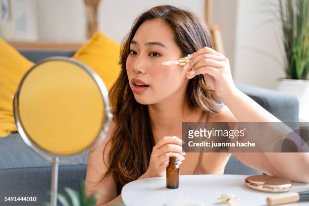 woman applying serum on her face. - oily skin stock pictures, royalty-free photos & images