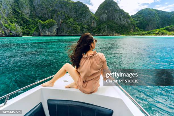 young woman on the bow of a speedboat at maya bay, a bay surrounded by mountains and emerald green waters at phi phi island. krabi province, thailand - phuket province 個照片及圖片檔