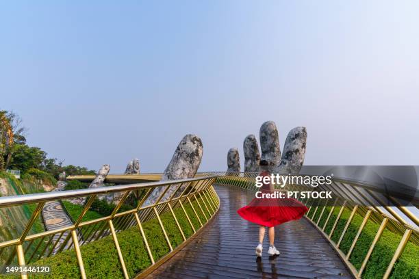 woman wearing red dress at golden bridge is a popular tourist attraction where tourists like to take pictures and this place has been published on various online media, increasing the number of tourists coming to ba na hills, da nang, the country. vietnam - mt dew stock pictures, royalty-free photos & images