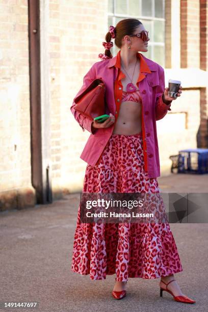 Guest wearing hot pink shacket, bra top, red oversized clutch and leopard pink maxi skirt at Afterpay Australian Fashion Week 2023 at Carriageworks...