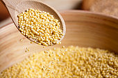 Hulled millet on wooden spoon and bowl