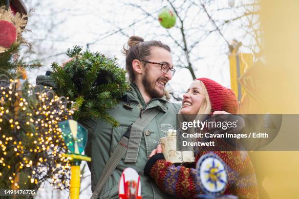 young man carrying christmas tree and embracing his girlfriend - munich christmas bildbanksfoton och bilder
