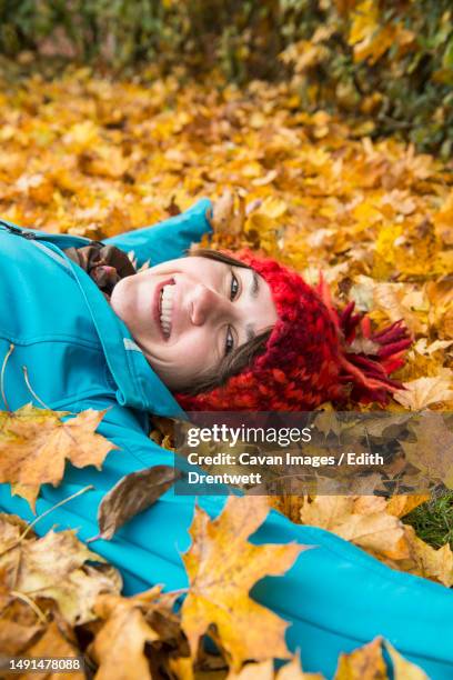 smiling woman lying on the ground in heap of autumn leaves - edith falls stock pictures, royalty-free photos & images