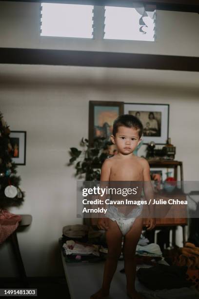 multiracial asian toddler boy standing on a table in his diaper - mililani stock-fotos und bilder