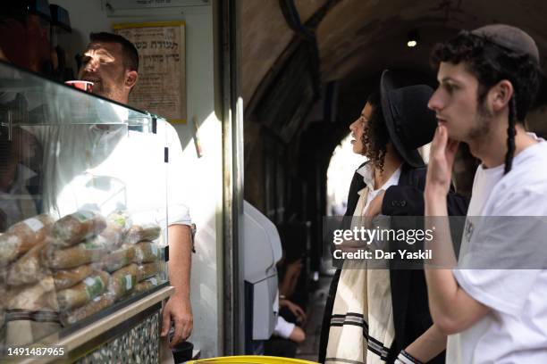 Young Orthodox Jewish men stop to buy food at the only Jewish-owned business in the Muslim Quarter on their way to the Western Wall on Jerusalem Day...