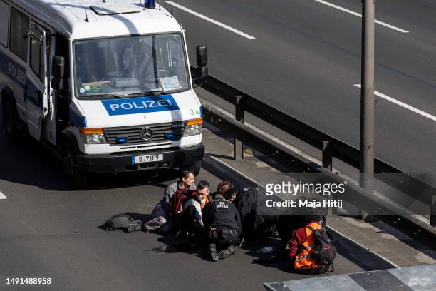 Climate activists from Last Generation , who have glued their hands to the asphalt on highway A100, are surrounded by police to be removed on May 19,...