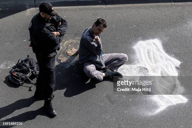 Climate activist from Last Generation , who has his hands glued to the asphalt on highway A100, is waiting to be removed by police on May 19, 2023 in...
