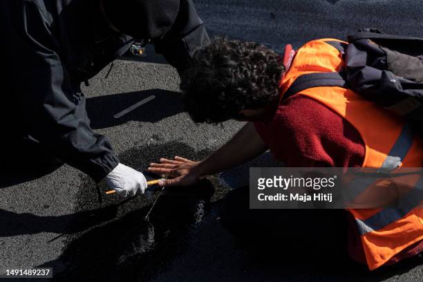 Climate activist from Last Generation , who has his hands glued to the asphalt on highway A100, is removed by police on May 19, 2023 in Berlin,...