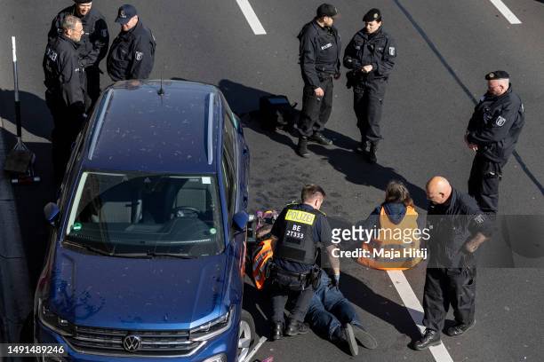 Climate activists from Last Generation , who have glued their hands to the asphalt on highway A100 and under a car, are surrounded by police to be...