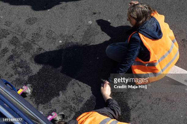 Climate activists from Last Generation , who have glued their hands to the asphalt on highway A100, hold their hands as they wait to be removed by...