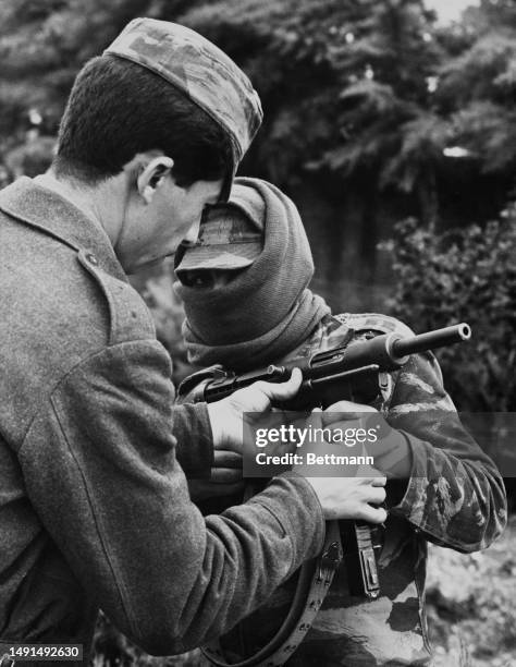 Fatah militiaman, his face covered by a scarf, receives instruction on how to handle his assault weapon at an unspecified location, April 19th 1969.