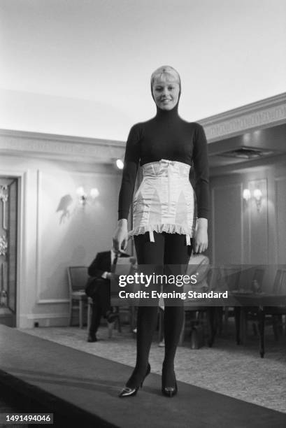 Model wearing a satin girdle over a black hooded catsuit at a French lingerie and nightwear fashion show, September 27th 1960.