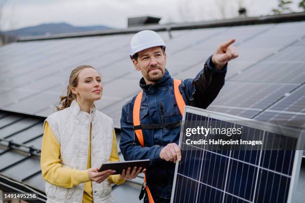 young woman talking with technician about solar panel system. - power occupation stock pictures, royalty-free photos & images