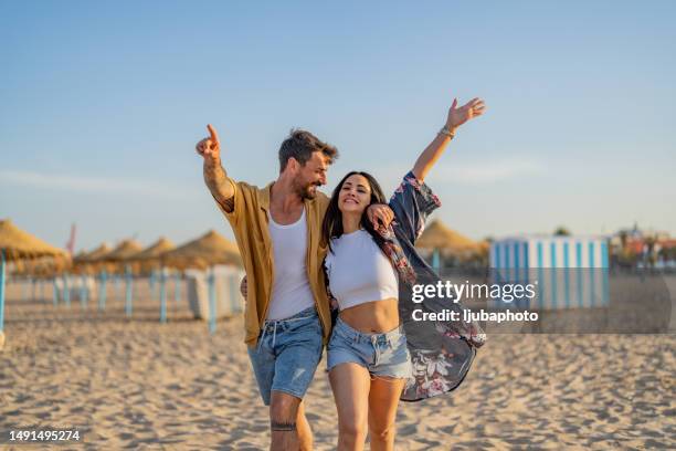 young couple spending time together at the beach, celebrating success. - vriendje stockfoto's en -beelden