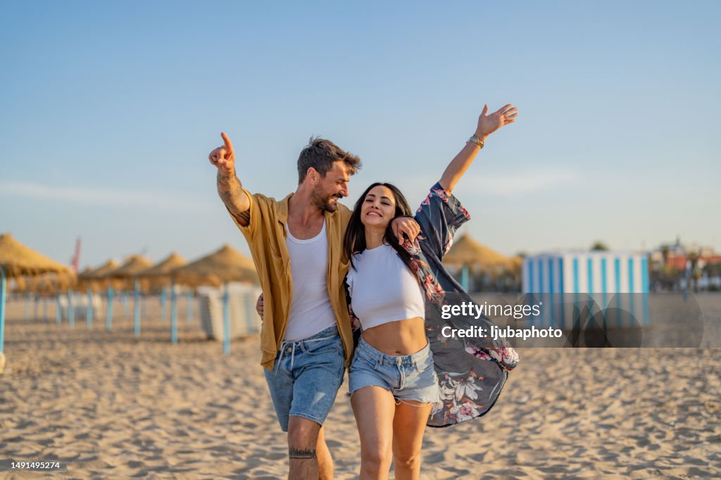 Young couple spending time together at the beach, celebrating success.