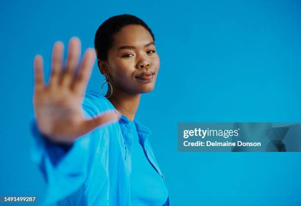 bella giovane donna nera che raggiunge la fotocamera mentre indossa una camicia blu e scatto superiore su uno sfondo blu con spazio di copia, foto d'archivio - studio head shot serious confident looking at camera foto e immagini stock