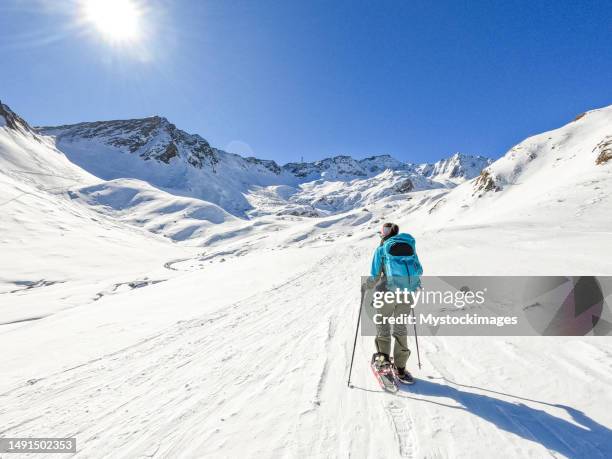 junge frau schneeschuhwandern im winter in den schweizer alpen - schneeschuh stock-fotos und bilder