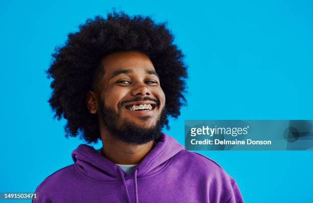 アフロの髪型の若い黒人男性がカメラを覗き込みながら、顔を向けて顔の側面を見て、コピー用スペースで微笑んでいる、ストック写真 - braces man ストックフォトと画像