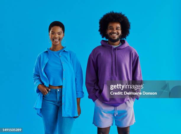 happy young black couple standing facing the front whilst looking into the camera smiling wearing casual clothing with their hands in there pocket, stock photo - black shirt 個照片及圖片檔