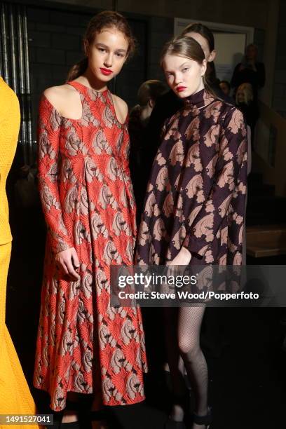 Backstage at the Emilia Wickstead show during London Fashion Week Autumn/Winter 2016/17, one model wears an empire line maxi dress in red and taupe...