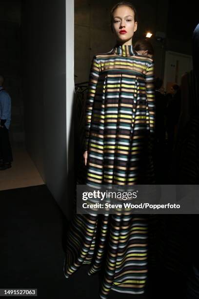 Backstage at the Emilia Wickstead show during London Fashion Week Autumn/Winter 2016/17, a model wears an empire line, long sleeved maxi dress in a...