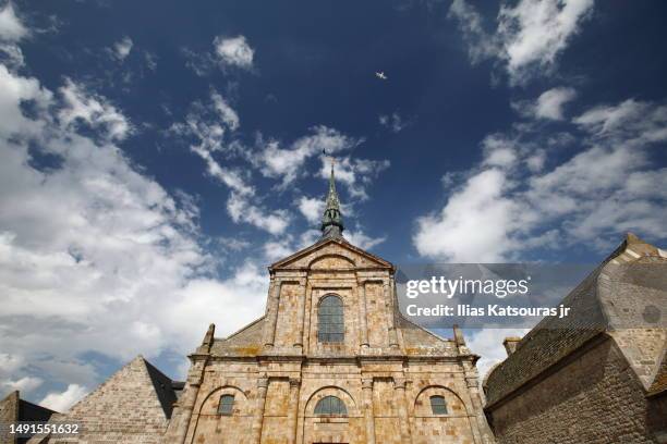 sunlit façade of the church-abbey saint-michel against a cloudy blue sky - abtei stock-fotos und bilder