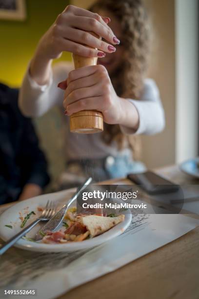 mulher que usa o moinho de pimenta na tabela de jantar - pepper mill - fotografias e filmes do acervo