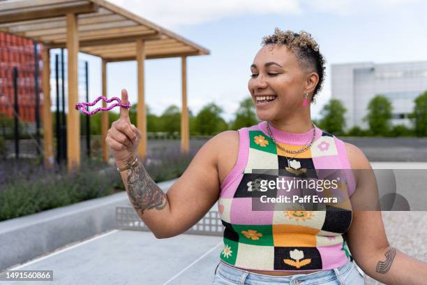 portrait of nonbinary autistic person outdoors with a stim toy - disabilitycollection stock pictures, royalty-free photos & images