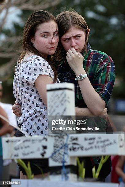 Two daughters of movie-theater-shooting-victim Gordon Cowden's embrace one another at the makeshift memorial built across the street from the Century...