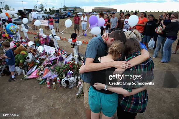 The children of movie-theater-shooting-victim Gordon Cowden embrace one another and pray at the makeshift memorial built across the street from the...