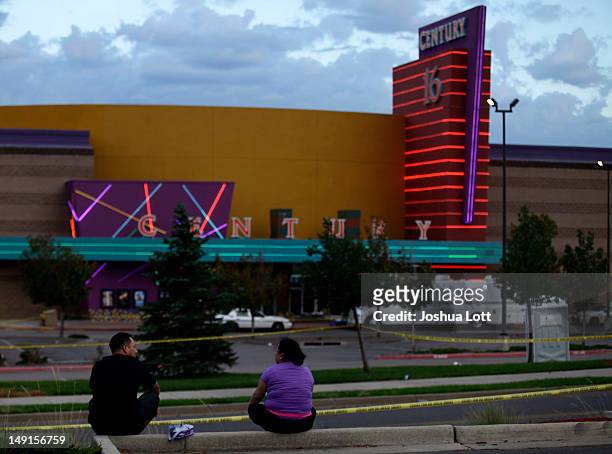 Two people sit across from the Century 16 movie theatre July 23, 2012 in Aurora, Colorado. Twenty-four-year-old James Holmes is suspected of killing...