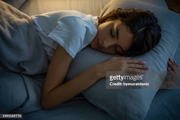 woman sleeping cozily on a bed in her bedroom at night - woman bedroom sleeping bildbanksfoton och bilder