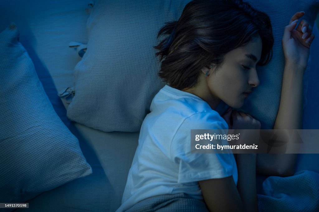 Mujer durmiendo cómodamente en una cama en su habitación por la noche