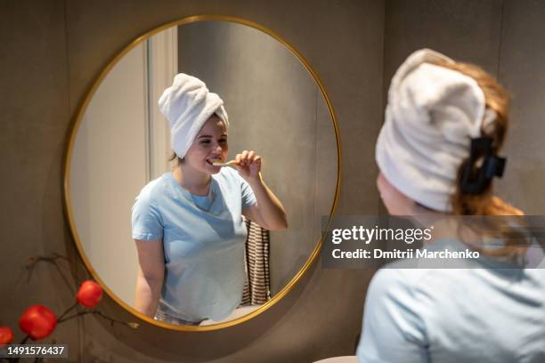 happy young woman brushing teeth after shower - bedtime stock pictures, royalty-free photos & images