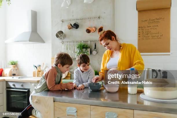 pregnant woman and her boys preparing breakfast in the kitchen - boy pajamas cereal stock pictures, royalty-free photos & images