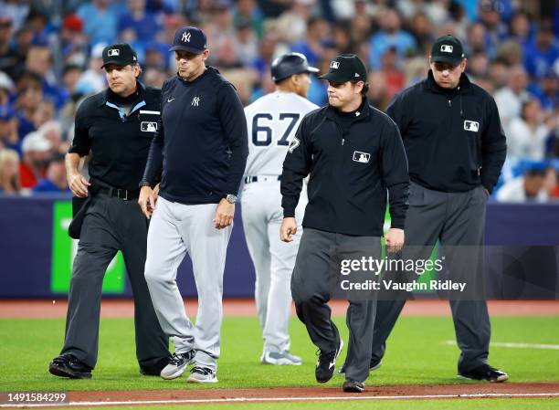 Manager Aaron Boone and Third Base Coach Luis Rojas of the New York Yankees speak to umpires during a game against the Toronto Blue Jays at Rogers...