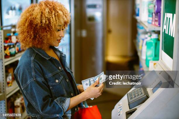 utilizzando il bancomat in un minimarket di los angeles - cash withdrawal foto e immagini stock