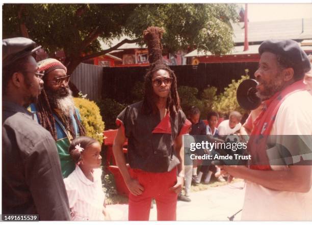 Rhythm guitarist and lead singer David Hinds middle and Steve Nisbett left of the English roots reggae band Steel Pulse an attendee far left talking...