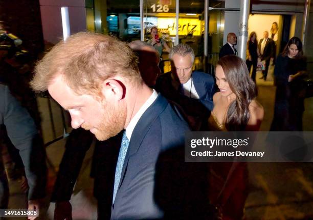 Security escorts Prince Harry, Duke of Sussex and Meghan Markle, Duchess of Sussex through a group of photographers outside The Ziegfeld Theatre on...