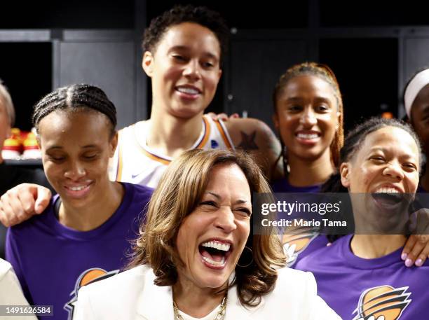 Vice President Kamala Harris laughs while standing with Brittney Griner and other members of the Phoenix Mercury in the locker room before their game...