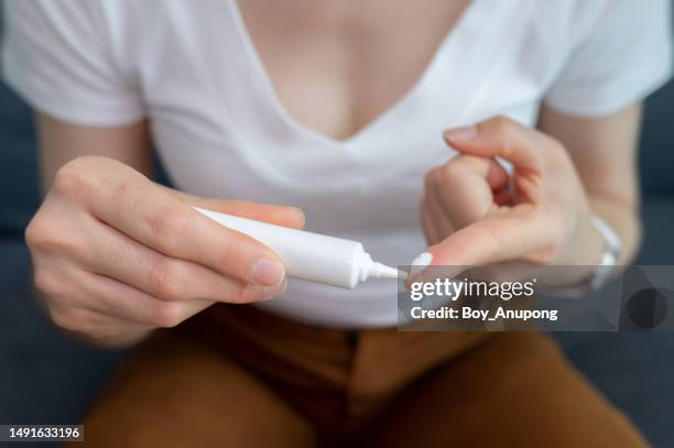 cropped shot of woman squeezes out cream from cosmetic tube. - cream tube stock pictures, royalty-free photos & images